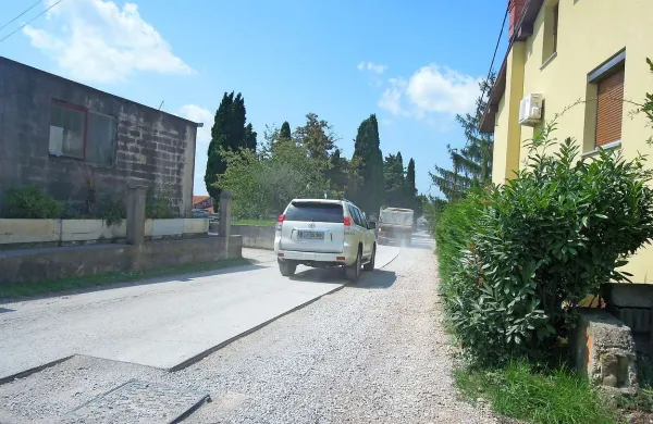Vozila dvigujejo prah, ki se polega na šmarske hiše in vrtove