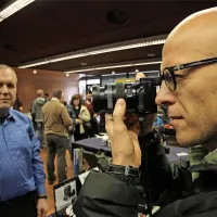 Delov fotoreporter Jure Eržen si ogleduje lahke lumixe, saj  je tradicionalna oprema zelo težka, sploh če jo nosiš ves dan.   