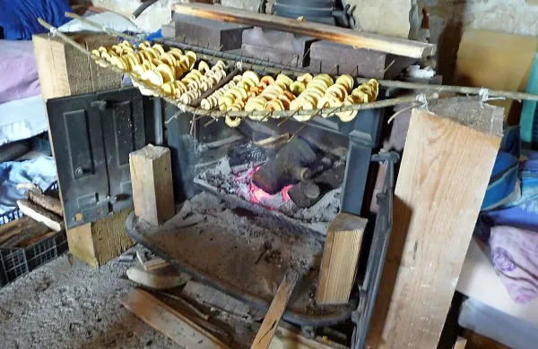 Nad litoželeznim kaminom se nataknjeni na lesene palčke sušijo jabolčni krhlji.