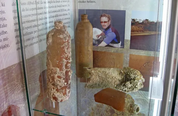 Glineni steklenici, ki ju je v slovenskem morju našel Alfred Zajič (na fotografiji v ozadju), razstavljajo v vitrini meseca v Pomorskem muzeju. 