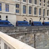 Stranski vhod na sodišče, kjer so parkirana policijska vozila.