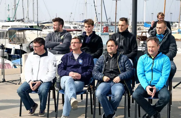 Akterji finala rokometnega pokala med torkovim žrebom v koprskem mandaraču. Koprska predstavnika, trener Zoran Jovičič 
in mladi igralec Tilen Sokolič sedita in stojita druga z leve.