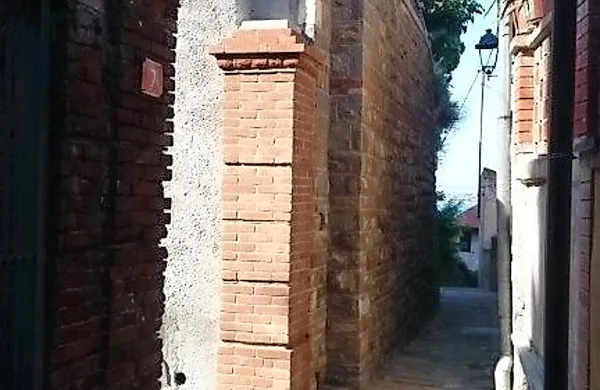Vrh kamnitega zidu je zaključen z opečnato čipkasto ograjo, 
po vzoru obstoječe ograje.
