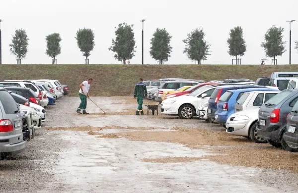 Delavci Komunale Koper so zjutraj v dežju krpali luknje na 
peščenem parkirišču.
