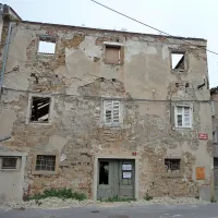 Skelet hiše na Tovarniški ulici 2 za Vojkovim nabrežjem se bo 
kmalu sesedel sam vase. Omet je odpadel z večine 
pročelja.