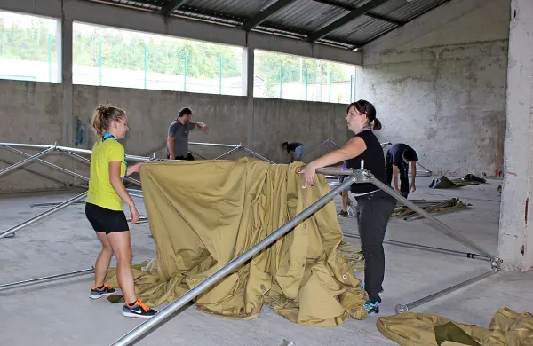 Postojnski taborniki so včeraj popoldan v hangarju ob centru za tujce postavljali šotore.