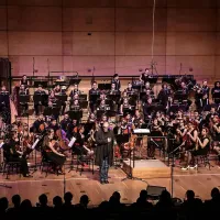 NOVA filharmonija na odru Gallusove dvorane, pred njimi 
stoji Boris Kobal.