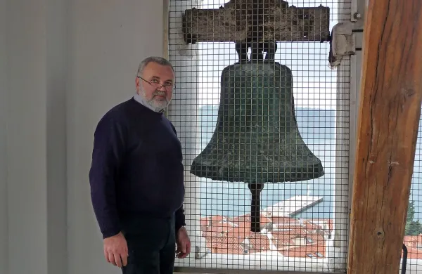 Župnik Janez Kobal ob najstarejšem zvonu, ki ga, edinega,    v 
času prve svetovne vojne niso predelali v orožje.