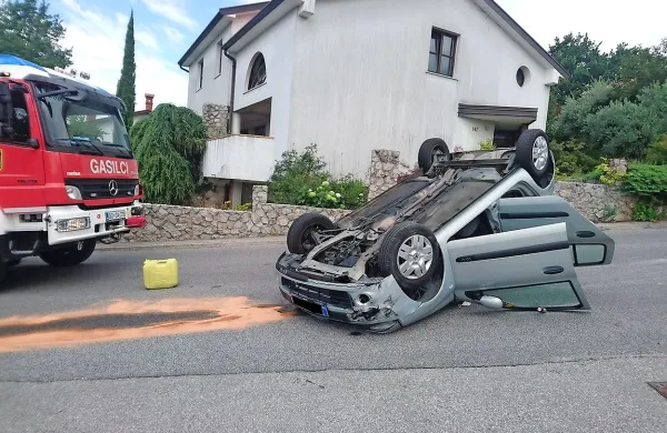 Voznik je z avtom zapeljal v robnik in se prevrnil na streho.