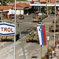 Nova slovenska zastava na mejnem prehodu, pod njo pa 
tanki.