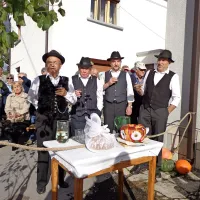 Vaški fantje ob mizi z nevestinim kolačem čakajo na ženina.