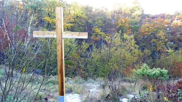 Križ na robu vhodnega brezna Kačne jame, ki označuje 
grobišče. V jami so posmrtni ostanki  domnevno 25 nemških 
vojakov. 