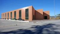Tako bo videti nova tovarna, z rdečkasto fasado in zelenimi stekli;  takšni sta tudi stavbi podjetij v Luciji.
