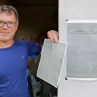 Andrej Colja pred hiško z kopijo članka Primorskih novic iz 
leta 1953