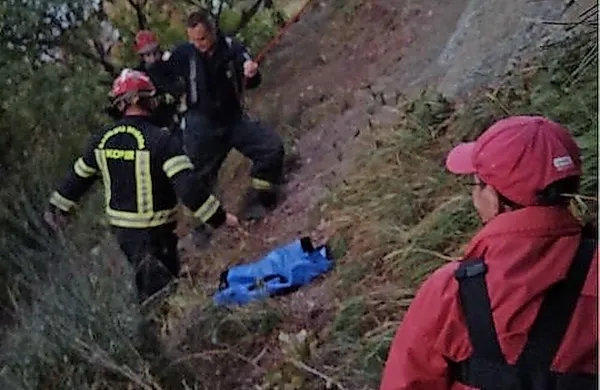 Po reševanju je gospa (desno) sledila gasilcem po strmem klifu. 