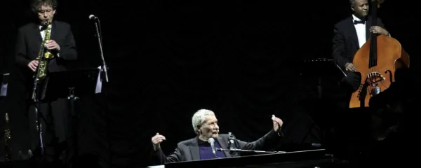 Paolo Conte, 82-letni pianist in pevec raskavega vokala, je svoji enajstčlanski glasbeni posadki poveljeval izza klavirja v osrčju odra. 