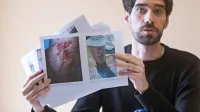 Miha Blažič iz Delovne skupine za azil kaže fotografije ranjenih  
migrantov, ki naj bi jih pretepli hrvaški policisti.