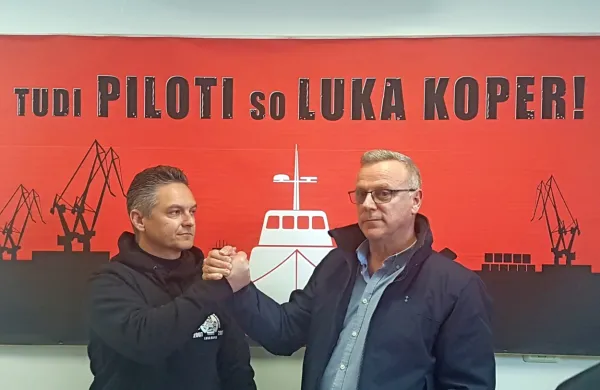 Pilot Maurizio Rasman in vodja pilotine Arjan Rapuš pred napisom 
Tudi Piloti so Luka Koper - izbira parole  spominja na dogajanje 
pred dvema letoma, ko je vodstvo Luke Koper hotelo odpustiti 
Mladena Jovičića in je sindikat žerjavistov  pred pristaniščem 
organiziral shode in proteste.  