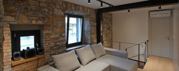 Udobna in svetla sedežna garnitura se prilega kamnitem ozadju.