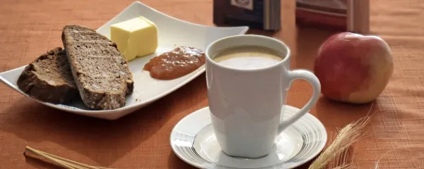 Polnozrnat kruh z maslom in marmelado, skodelica Kneippove 
kave in jabolko za zdrav zajtrk.