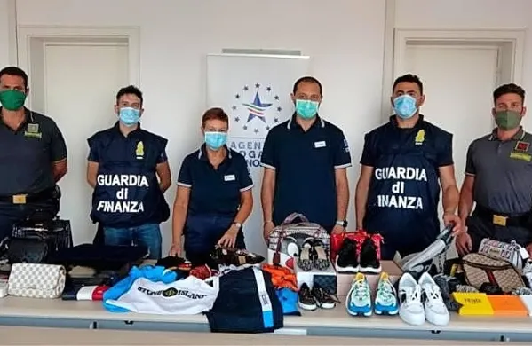 Tržaška finančna straža in carinska uprava sta v minulih dneh v 
tržaškem novem pristanišču zasegli več kot 230.000 ponarejenih 
kosov oblačil, torbic in obutve v vrednosti 20 milijonov evrov. 
(Foto vir: Primorski dnevnik)