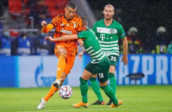 Miha Blažič  opazuje, kako poskuša soigralec  zaustaviti Cristiana 
Ronalda na dvoboju med Ferencvarosem in Juventusom.
