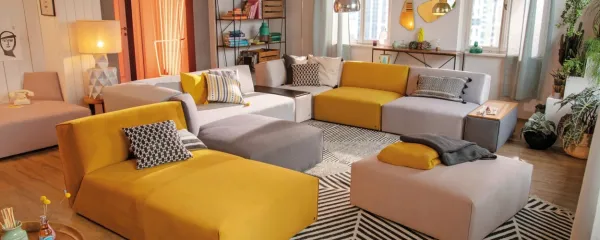 Rumena prostor otopli, siva mu doda eleganco. Modularne zofe 
Tom Tailor.