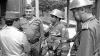 Slavko Gerzelj (levo) na fotografiji Davorina Križmančiča med pogajanji z oficirji JLA 
na mejnem prehodu Pesek. Kasneje je z nasmehom razvil slovensko zastavo.