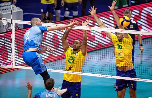 Alen Pajenk pošilja žogo čez mrežo, pod katero je  s številko 21   Alan Souza, ki je izstopal v brazilski reprezentanci. 