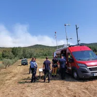 Štab gasilcev v Kostanjevici na Krasu, v ozadju dim, ki se širi ob 
požaru