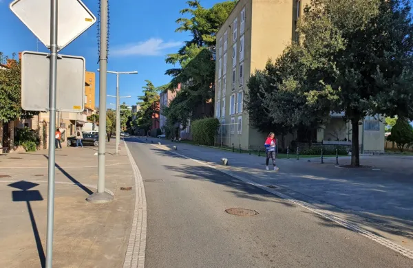 V križišču Vojkovega nabrežja s krakom Ferrarske ulice je pri stavbi 
Villa Domus zaradi nepreglednosti in ozkega prostora za vodenje 
nemotornega prometa ob obstoječem prehodu za pešce predviden zaris prehoda za kolesarje s polno rdečo površino. Foto vir: 
Arhiv MOK