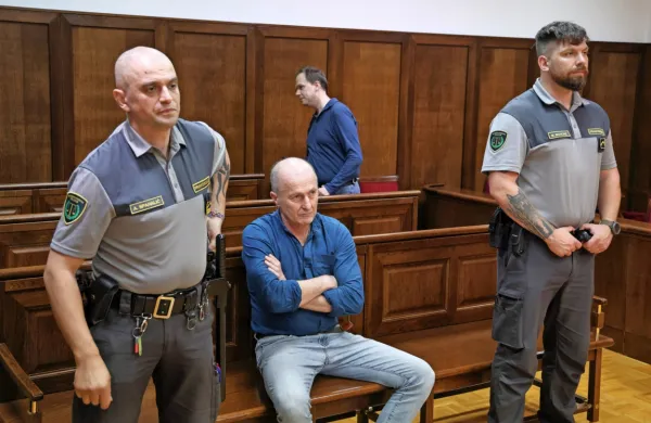 Adriano  Petelin  (na  klopi  med  pravosodnima  policistoma)  naj  bi  
po  obtožnici  Darja  Grmeka  umoril  iz  koristoljubnosti.  