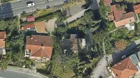 V sredini fotografije je Kosmačeva hiša s temno streho, kot je videti 
iz zraka, okoli nje pa park s stoletnimi drevesi. 