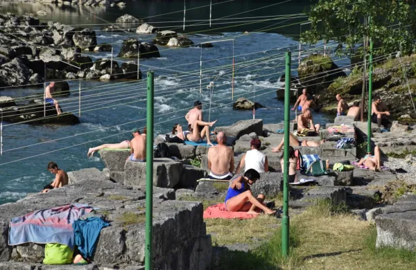 Na obali pri kajakaškem centru se večina  sonči. Nekateri se 
osvežijo v mirni vodi, nekateri pa tudi tvegajo s plavanjem čez 
brzice na nasprotni breg Soče.