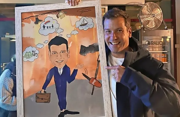 Gregor Trebušak s karikaturo, ki so mu jo podarili sodelavci.
