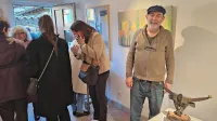 Edo Zanco na razstavi ob kipu boškarina, v ozadju ena izmed slik, levo nasmejana  gostiteljica Graziella Ponis 
Sodnikar

