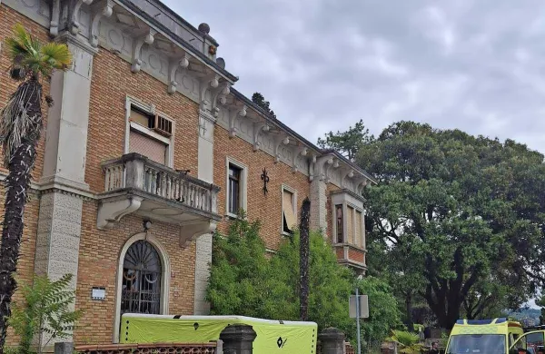 Pod zapuščeno stavbo so gasilci namestili blazino, če bi moški skočil. 