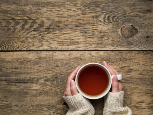 Female hands holding a mug of hot black tea. Cold winter white warm clothes. Top view. Aged rustic wooden background,Image: 1023786489, License: Royalty-free, Restrictions:, Model Release: no, Credit line: Natalia Gdovskaia/imageBROKER/Profimedia