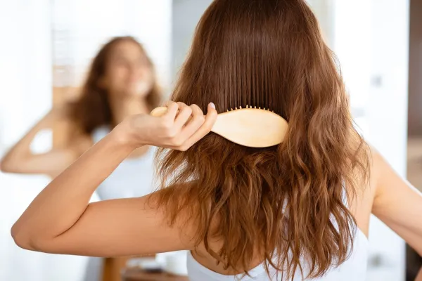 Back View Of Woman Brushing Hair With Hairbrush Standing Near Mirror In Modern Bathroom Indoor. Unrecognizable Lady Combing And Untangling Wavy Brown Hair At Home. Selective Focus,Image: 1023545465, License: Royalty-free, Restrictions:, Model Release: no, Credit line: Prostock-studio/Alamy/Profimedia