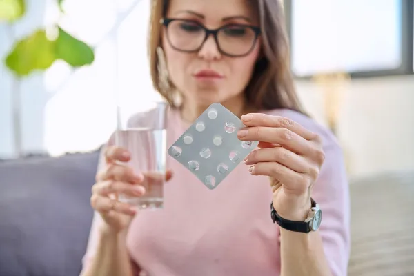 Middle aged woman taking medicine, in home interior. Serious female holding blister of pills and glass of water. Medicine, treatment, health, healthcare, mature people concept,Image: 987173786, License: Royalty-free, Restrictions:, Model Release: yes, Credit line: Valerii Honcharuk/Alamy/Profimedia