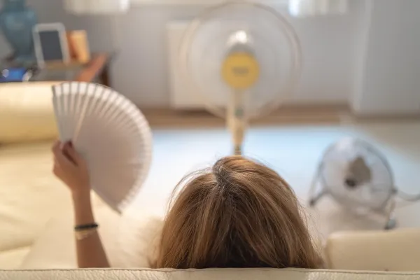 Woman sitting on a sofa with several fans giving her air and a fan in her hand, high summer temperatures,Image: 710020270, License: Royalty-free, Restrictions:, Model Release: yes, Credit line: Jose Miguel Sanchez/Alamy/Profimedia