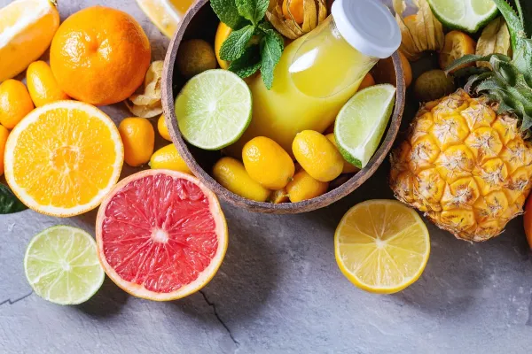 Variety of whole and sliced citrus fruits pineapple, grapefruit, lemon, lime, kumquat, clementine and physalis with mint and bottle of juice in bowl over gray textured background. Top view with space.,Image: 315227824, License: Royalty-free, Restrictions:, Model Release: no, Credit line: Natasha Breen/Alamy/Profimedia