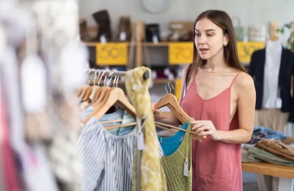 Young woman standing near clothes hangers. Female buyer choosing summer dresses on sale,Image: 1088172315, License: Royalty-free, Restrictions:, Model Release: no, Credit line: Iakov Filimonov/Alamy/Profimedia