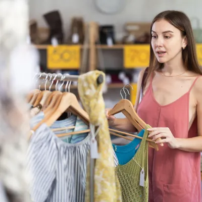Young woman standing near clothes hangers. Female buyer choosing summer dresses on sale,Image: 1088172315, License: Royalty-free, Restrictions:, Model Release: no, Credit line: Iakov Filimonov/Alamy/Profimedia