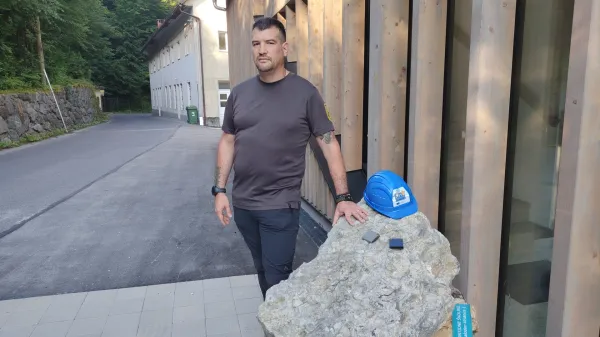 Okolica Idrije, pred Divjo bajto pri vstopu v krajinski park Zgornja Idrijca. Najditelj fosila naravovarstveni nadzornik v tem krajinskem parku Gregor Kozelj pri kamnini s skoljkami srcankami, ki so bile hrana plakodontom. 