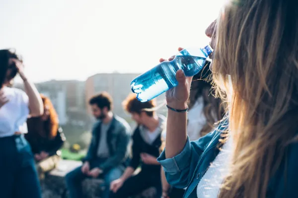 Group of friends enjoying roof party, young woman drinking from water bottle,Image: 335976819, License: Royalty-free, Restrictions: Specifically, you may not use the Images in ways or contexts that might reasonably be construed as pornographic, defamatory, libellous or otherwise unlawful;Specifically, you may not use images depicting any model in any unduly controversial or unflattering context, unless accompanied with a statement indicating that the person is a model and the images are being used for illustrative purposes only., Model Release: yes, Credit line: Eugenio Marongiu/ImageSource/Profimedia