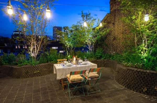 Evening shot of a roof terrace designed by Todd Longstaffe-Gowan in Mayfair. Traditional brick pavers paving and raised beds build with matching bricks. Mixed planting of specimen small trees and low underplanting. Modern garden lighting. garden construction by The Garden Builders.,Image: 317675488, License: Rights-managed, Restrictions:, Model Release: no, Credit line: Jacek Wac/Alamy/Profimedia