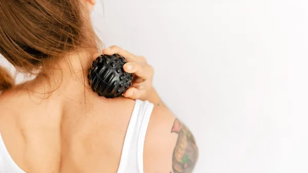 Closeup of unrecognizable woman using massage ball on neck for trigger point therapy. Active lifestyle, calisthenics recovery, and fitness at home concept with copy space on white wall.,Image: 1112172988, License: Royalty-free, Restrictions:, Model Release: no, Credit line: Aliaksei Kruhlenia/Alamy/Profimedia