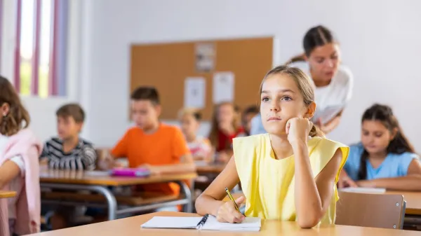 Young girl sitting at desk with her classmates during lesson in school and writing in copybook.,Image: 1023553991, License: Royalty-free, Restrictions:, Model Release: no, Credit line: Iakov Filimonov/Alamy/Profimedia
