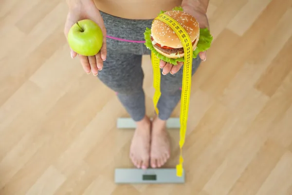 Diet concept, woman holding a choice of harmful hamburger and fresh apple.,Image: 560766212, License: Royalty-free, Restrictions:, Model Release: no, Credit line: Iurii Maksymiv/Alamy/Profimedia